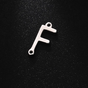 Macro detail of silver F-shaped letter pendant with dual attachment holes
