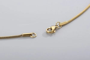 Macro shot of 18k gold plated lobster clasp on a stainless steel round snake chain