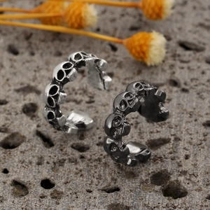 Close-up of vintage skull chain earrings in silver and gun black on a rock surface