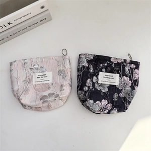 Detail of floral jacquard pouches in pink and black colors with metal pull tabs