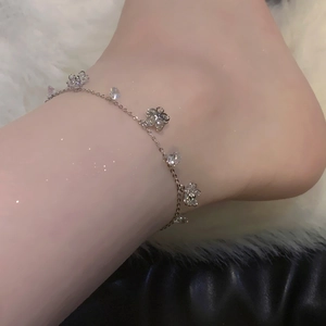 Silver flower anklet with sparkling zircon crystals worn by a model on a soft background