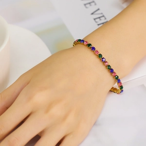Close-up of bohemian gold bracelet with colorful zircons worn on wrist in a clean setting