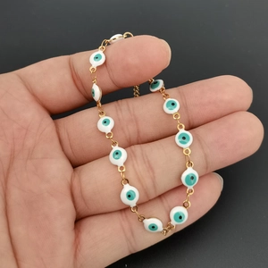 Detail of Turkish Evil Eye bracelet with golden chain and blue enamel charms on hand