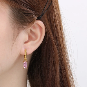 Détail de la boucle d'oreille zircon rose rectangulaire et texture martelée dorée