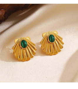 Close-up of gold shell earrings with green malachite stones on soft beige silk fabric
