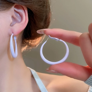 Close-up of white glossy hoop earrings worn by a model showcasing the minimalist design