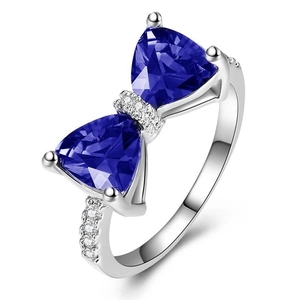 Close-up of bow ring featuring blue triangle gemstones and white zircon pavé details