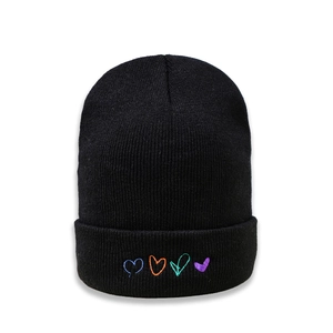 Détail du bonnet noir avec quatre cœurs colorés brodés sur le bord replié du chapeau