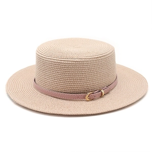 Détail du chapeau de paille à haut plat avec ruban en cuir rose et boucle dorée élégante