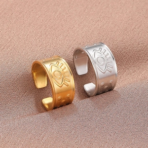 Detailed close-up of gold and silver open rings with engraved evil eye totem and dot reliefs