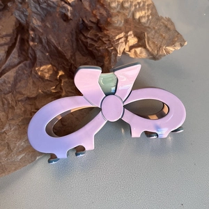 Detail showing a large lilac acetate hair claw with a green color-contrast bow design