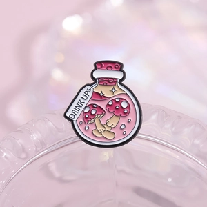 Pink magic potion bottle enamel pin featuring mushrooms and Drink Up tag accessory