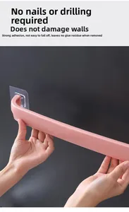 Pink drill-free towel rack being installed on a wall with transparent adhesive