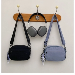Détail de sacs bandoulière en nylon imperméable noir et bleu avec pendentifs oursons