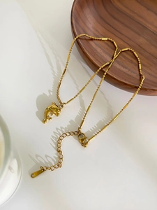 Close-up of golden dolphin pendant with beaded chain and secure lobster clasp on necklace