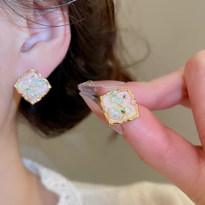 Detailed view of elegant gold-tone pearl earrings with floral enamel and gems