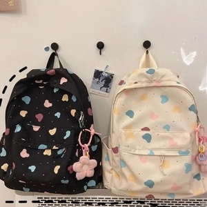 Detail of cute polka dot printed backpacks in black and cream with floral plush pendants