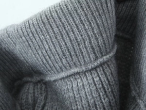 Macro shot of dark grey chunky knit wool blend fabric showing thick ribbed texture detail