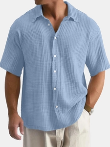 Close-up of light blue short sleeve shirt showing vertical crinkle texture and button detail
