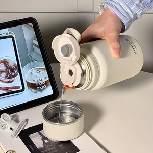 Cream stainless steel vacuum flask showing dynamic water pouring in office setting