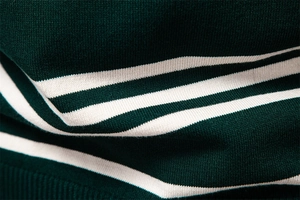 Close-up of dark green knitted sweater fabric with crisp white stripe texture detail