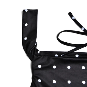 Detailed view of black polka dot fabric with wide shoulder strap and elastic texture