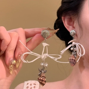 Detail of seashell stud earrings with woven bow, pearls and starfish charms