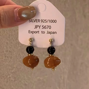 Détail de boucles d'oreilles géométriques en résine avec tiges en argent 925 sur étiquette