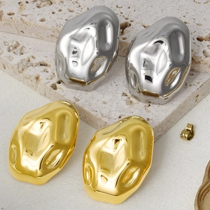 Macro shot of irregular lava-textured earrings in gold and silver on stone