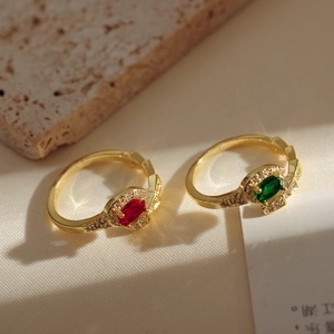 Detailed macro view of 18K gold plated snake rings with red and green oval gemstones