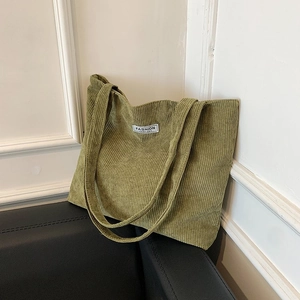 Detail of green corduroy tote bag showing ribbed texture and fashion woven label