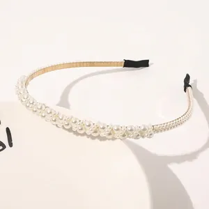 Detail of elegant faux pearl headband with layered white beads on slim gold metal frame