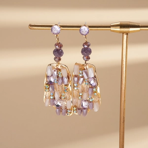 Close-up of bohemian gold earrings with purple crystals and vintage beaded tassels