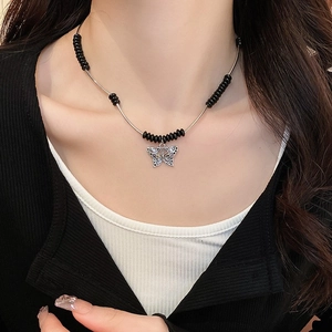 Detail of butterfly pendant necklace with black rice beads and silver metal tubes