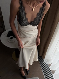 Detail of satin slip dress featuring elegant black lace trim and silk-like beige fabric