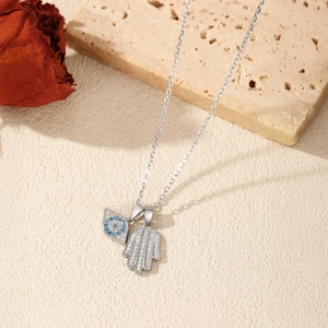 Sparkling S925 sterling silver Hamsa hand and Evil Eye pendant necklace on a textured background