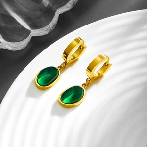 Detailed close-up of golden butterfly earrings with elegant green oval stones and tassels