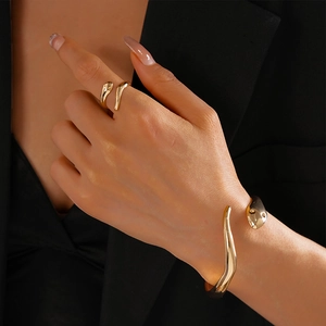 Detail of elegant gold snake-shaped open bracelet and ring set on model wrist