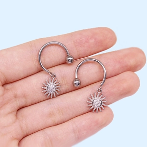 Detailed view of silver sun-shaped nipple rings with sparkling cubic zirconia stones