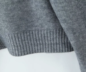 Detailed macro view of the grey knit cardigan showing high-quality ribbed cuffs and texture