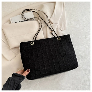Detail of black tweed texture and gold metal rings on a French-style tote bag