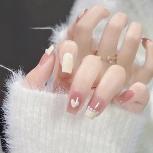 Detail of short square press-on nails with yellow and lavender heart and pearl accents