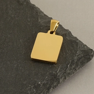 Close-up of a minimalist square gold pendant on a textured slate background