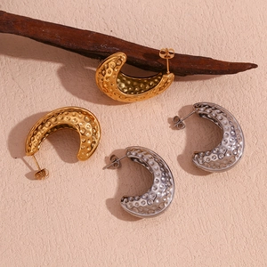 Détail de boucles d'oreilles croissant avec texture en métal martelé en doré et argenté