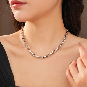 Close-up of a silver metal chain necklace with unique rectangular links on a model