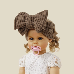 Detail of brown knitted bow headband on a lifelike baby doll with blonde hair