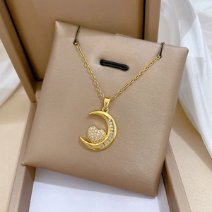 Dettaglio di un ciondolo a luna e cuore dorato con cristalli in una confezione