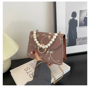 Detail of floral embroidery and elegant pearl handle on a vintage style crossbody bag