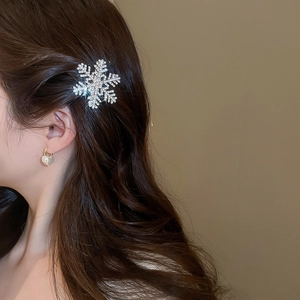 Detail of snowflake diamond hair clip and heart pearl earrings worn by a model