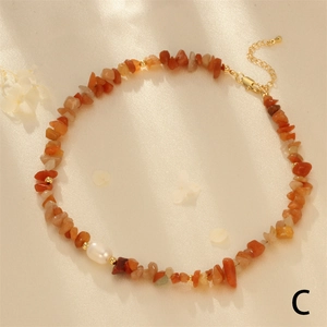 Close-up of orange gemstone beaded necklace with white pearl on silk fabric